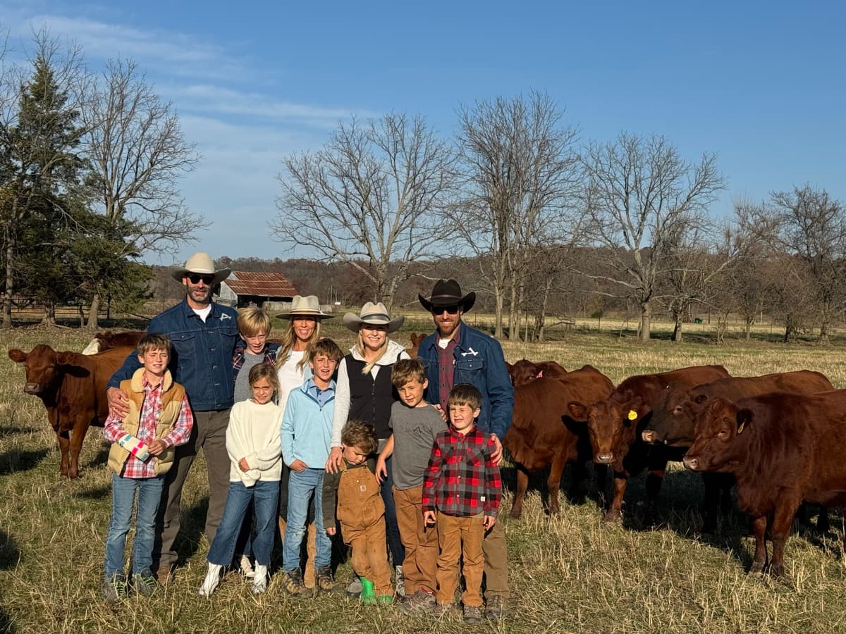 Two families with their kids standing among the cattle